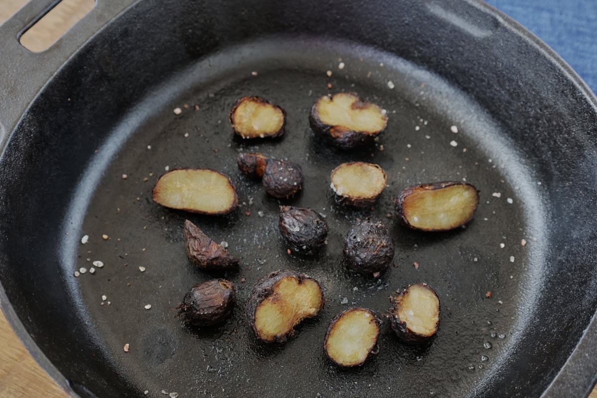 roasted african potato mint tubers in a cast iron pan with coarse salt and a napkin in the background