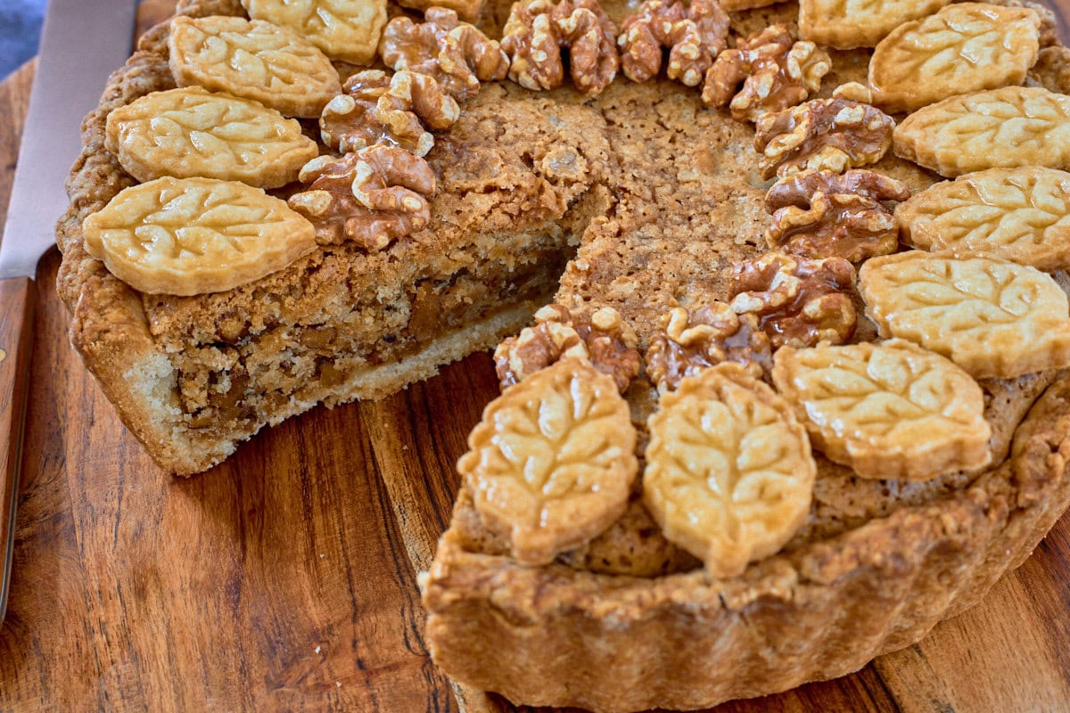 a tart on a cutting board with a slice removed and a knife alongside