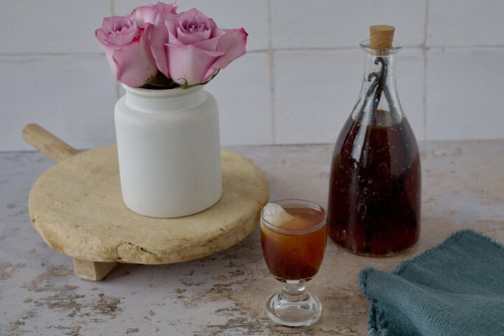 a tray with a vase of flowers on it, a bottle and glass of liqueur, and a napkin