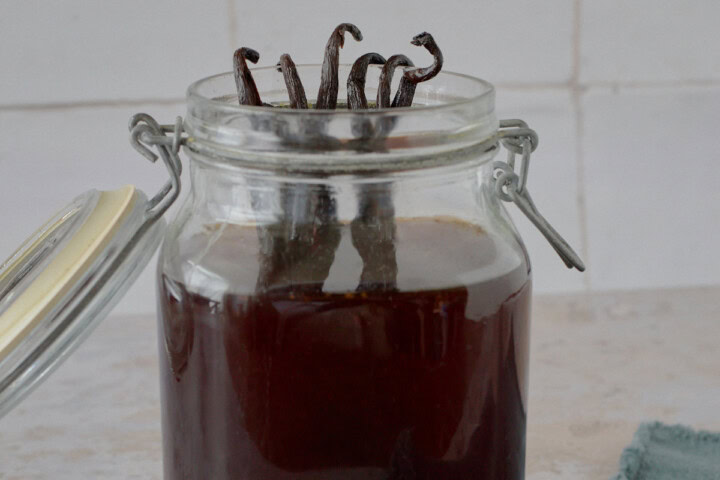 an open jar of liqueur with vanilla beans and a napkin