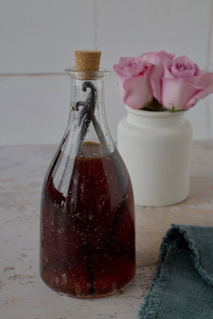 a bottle of liqueur, vase of roses, and napkin